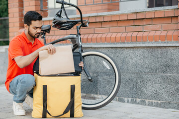 Courier on bicycle in protective helmet delivering food in city and online order