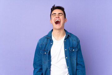 Obraz premium Teenager caucasian handsome man isolated on purple background shouting to the front with mouth wide open