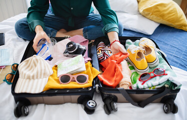 Unrecognizable woman with suitcase packing for holiday at home, coronavirus concept.