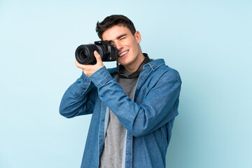 Teenager photographer man isolated on blue background