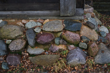 The wall of an old wooden house on a stone foundation. Rock Wall Foundation.