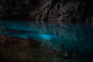 Light descends into the darkness of a submerged cavern with blue lake. Concept of travel and adventure.