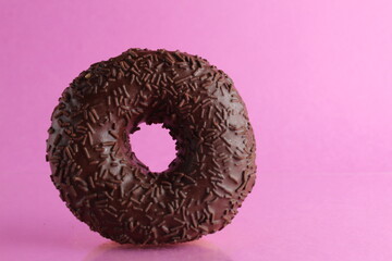 Chocolate berliner doughnut on a pink background with a place to text a copyspace breakfast dessert national dish