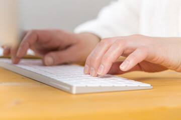 Woman office worker typing on white keyboard