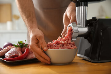 Man using modern meat grinder in kitchen, closeup