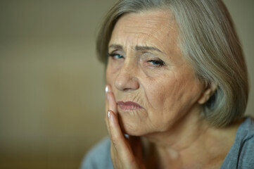 Close up portrait of sad senior woman with toothache