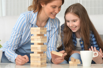 Happy girl and mother playing with blocks at home
