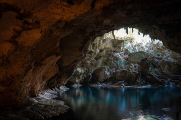 Light descends into the darkness of a submerged cavern with blue lake. Concept of travel and adventure.