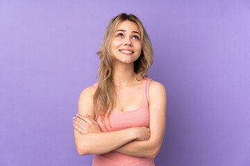 Teenager Russian girl isolated on purple background looking up while smiling