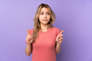 Teenager Russian girl isolated on purple background with fingers crossing and wishing the best