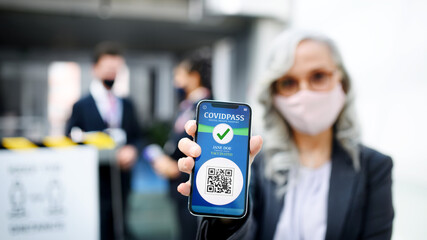 Senior woman showing smartphone with covidpass, coronavirus, travel and new normal.