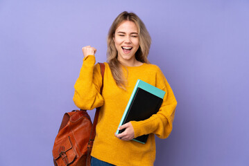 Teenager Russian student girl isolated on purple background celebrating a victory