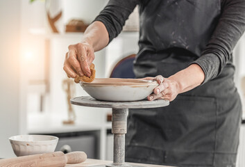 Woman forming plate on pottery wheel
