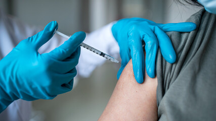 Unrecognizable woman getting vaccinated in hospital, coronavirus and vaccination concept.