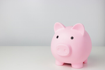 Pink piggy bank stands up on white table isolated on white background with copy space. Money deposit and finance concept.