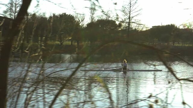 Cinematic stabilized video of rower on lake in downtown austin texas at sunset, healthy lifestyle activities