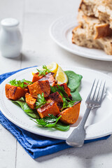 Baked sweet potato salad with spinach on white plate.