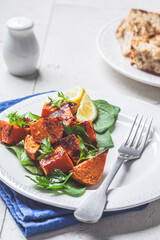 Baked sweet potato salad with spinach on white plate.