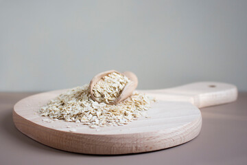 Scoop with raw oatmeal on a wooden board. Concept of healthy eating, vegan food, breakfast and medecine for overlay on product presentation, mockup, template, posters and wallpapers. Copy space.