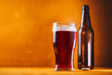 Cherry beer pint glass, summer cold berry low-alcohol radler drink. Wooden background