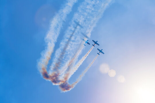 Flight team of three turboprop planes makes a loop in the sky lit by a bright sun.