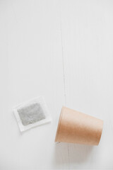 Paper cup and square dry tea bag on a white background. Top view. Copy, empty space for text