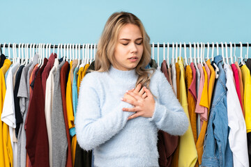 Teenager Russian girl buying some clothes isolated on blue background having a pain in the heart