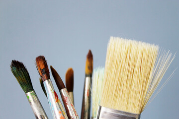 Old and new brushes with dried paint on a gray background. Artistic background