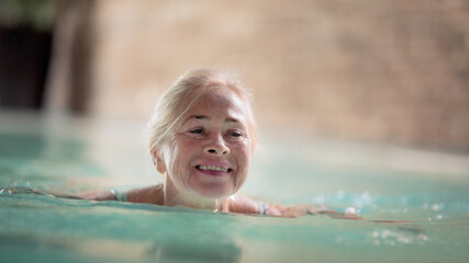 Portrait of senior woman in indoor swimming pool, swimming.