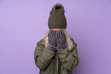 Teenager blonde girl with winter hat over isolated purple background with tired and sick expression