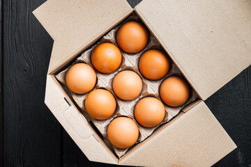 Fresh eggs on paper egg box, on black wooden table background, top view flat lay