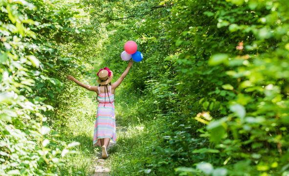happy child girl in straw hat with rose flowers in summer nature with balloons, birthday.