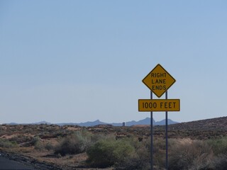 Roadside sign warning drivers the right lane ends in 1000 feet in Arizona.