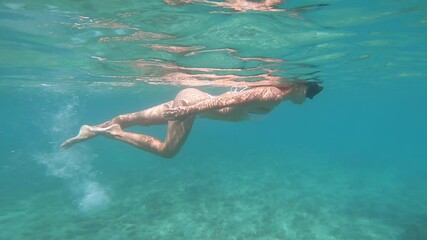 Woman swimming underwater. Concept about vacations and nature. Shot taken with underwater camera