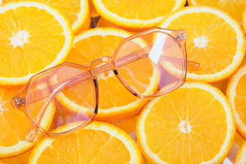 stylish laza glasses on round orange slices, orange pattern on the background