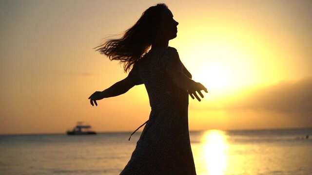 Carefree and happy woman dancing during sunset at the seascape. concept of healthy lifestyle and love of life