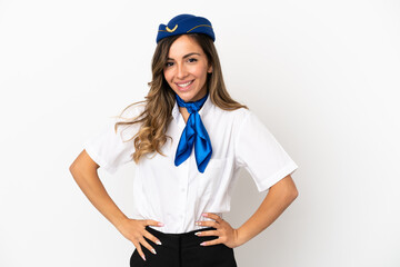 Airplane stewardess over isolated white background posing with arms at hip and smiling
