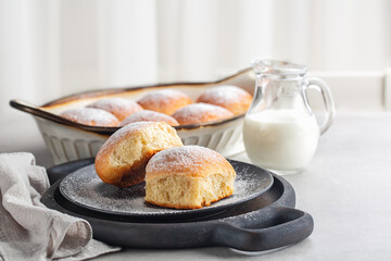 Breakfast with sweet bread rolls powdered with sugar. Jag of milk. Selective focus. Light...