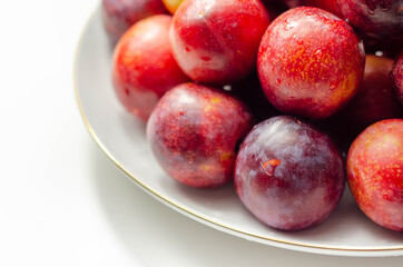 Obraz premium Closeup on fresh and ripe plums on a white ceramic plate
