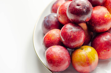 Closeup on fresh and ripe plums on a white ceramic plate