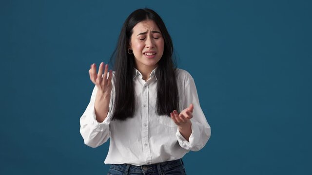 A confused korean woman is showing face-palm gesture standing isolated over blue wall in studio