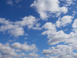Natural sunny blue sky background with beautiful lush white cumulus clouds and fluffy cirrus clouds
