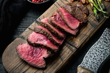 Sliced grilled marbled meat steak Filet Mignon, with onion and asparagus, on wooden serving board,...