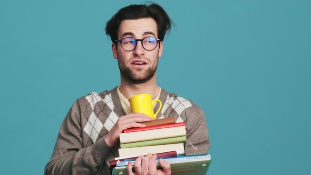 The surprised man abruptly getting-up with a stack of books looking around and gradually sitting-down in them while leaving the frame in the studio