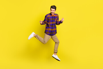 Fototapeta na wymiar Photo of positive guy jump hold fists wear bow tie checkered shirt pants sneakers isolated yellow color background