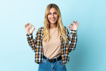 Obraz premium Young blonde Uruguayan isolated on blue background showing ok sign with two hands