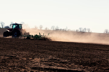 Tractor Plowing Agricultural Field in the Spring . Dust over the agricultural field
