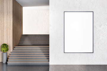 Blank white poster in black frame on light concrete wall outdoors with black wooden stairs with...