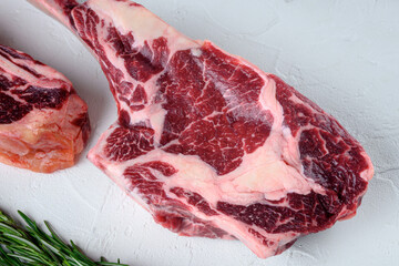 Tomahawk beef steak raw, on white stone  background, top view flat lay