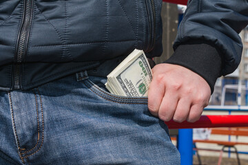Man pulls out a large bundle of money from his jeans pocket